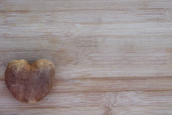 heart shaped potato on wood background with copy space