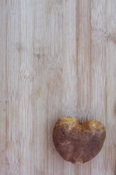 heart shaped potato on wood background with copy space