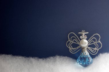 Mavi ve gümüş melek süslemesi beyaz kar üzerine koyu mavi arkaplan ve kopyalama alanı