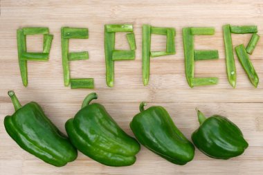 Dört olgun yeşil biber ve parça parça kelime biber