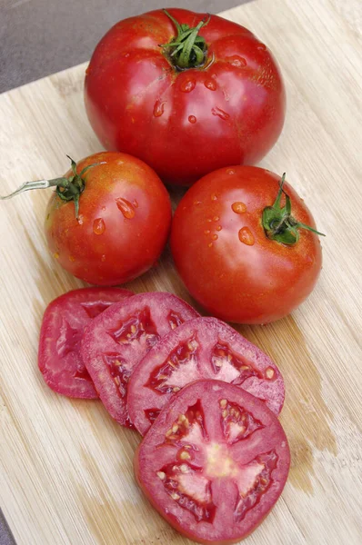 Drei Saftige Rote Nasse Tomaten Mit Scheiben Auf Hellem Holzhintergrund — Stockfoto