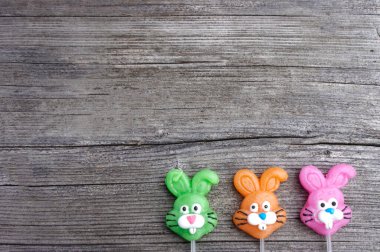 Kopya alanı olan ahşap bir arka planda üç şekerleme tavşanı.