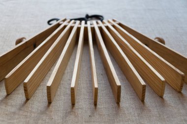 Slav halk gürültüsü müzik enstrümanı - birbirine bağlı ahşap kalaslardan yapılmış bir cırcır (treshchotka), arka planda gri keten bir arka plana karşı