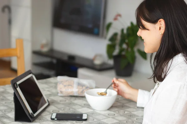 Young beautiful woman using digital tablet while healthy breakfast — Stock Photo, Image