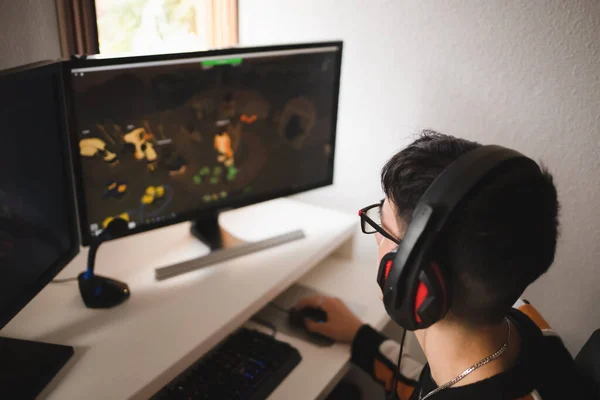 Achteraanzicht van geconcentreerde jonge gamer in koptelefoon en bril met behulp van computer — Stockfoto