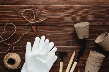 Bahçıvanlık. Bahçe aletleri ve ahşap arka planda eldivenli eko kaplar. Üst görünüm.