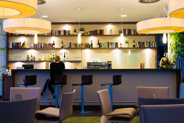 Lonely girl sits alone at modern illuminated hotel bar — Stock Photo, Image