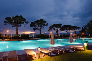 havuz kenarı ağaçları ile gün batımında güneş şezlong