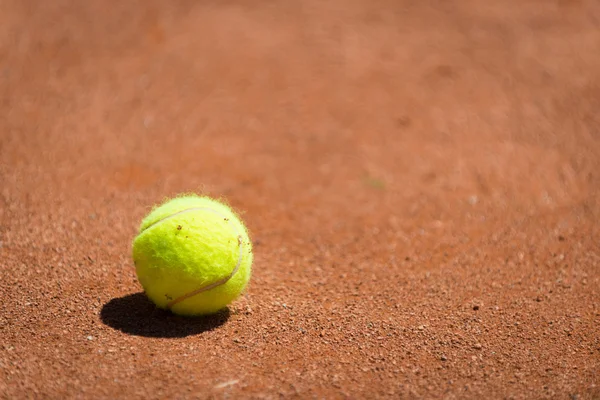 Yellow tennis ball on orange sand — Stock Photo, Image