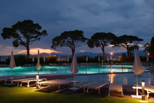 Zona de piscina del hotel al atardecer con árboles y tumbonas — Foto de Stock