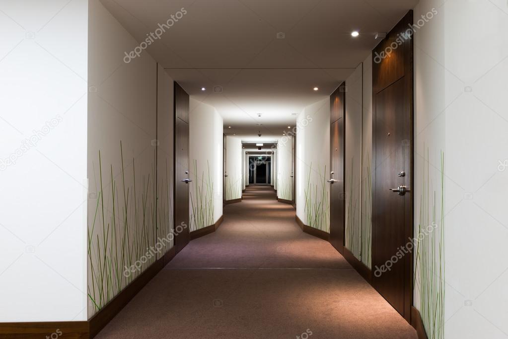 Long hotel corridor with doors and green grass wallpaper