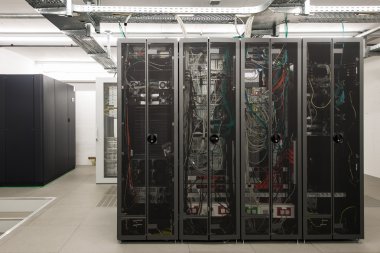 Backside of arranged black server racks in small computer room clipart