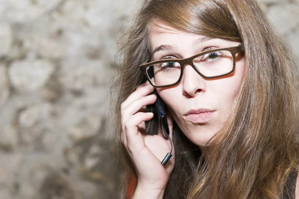 Aantrekkelijke jonge vrouw reageren in verrassing aan het gesprek op een mobiele, natuurlijke expressie met copysapce bril Stockafbeelding