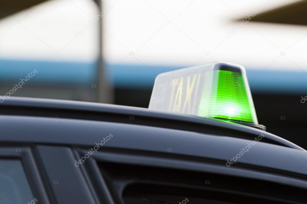 Closeup of a green light on a taxi cab indicating that it is available for hire as it waits in line