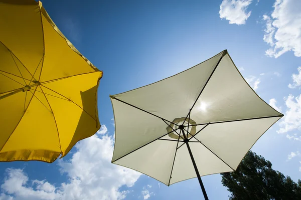 Vita och gula parasoll på underbar sommardag med blå himmel och några moln — Stockfoto