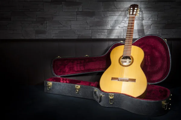 Beleuchtete klassische Musikgitarre mit Etui vor Leder und Steinwand — Stockfoto