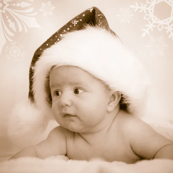 Рождественский ребенок в кепке и с поднятой головой лежит на белом одеяле — стоковое фото