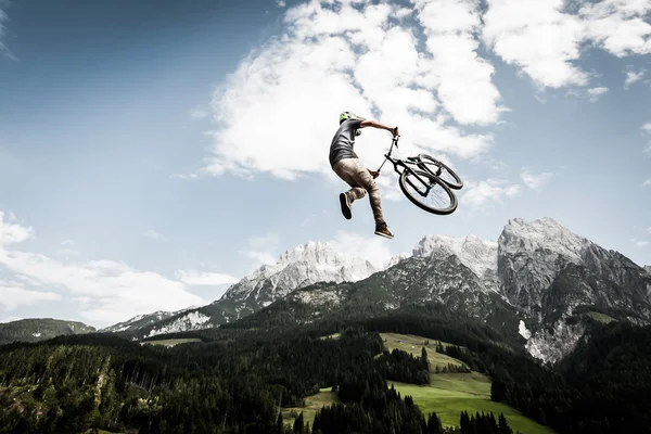Biker springt einen hohen Stunt mit Bergen im Rücken — Stockfoto