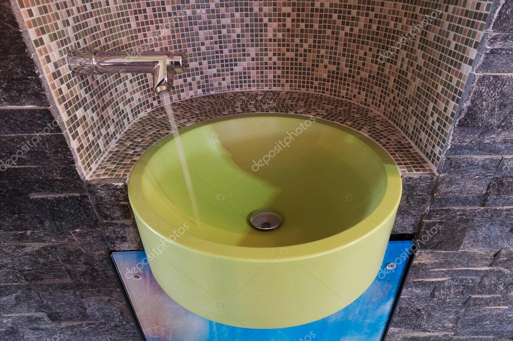 Lavabo sobre encimera verde con grifo de agua asentada con azulejos de