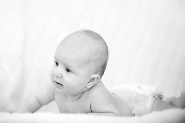 Sceptic baby boy lifts up his head and is looking what's going on — Stock Photo, Image