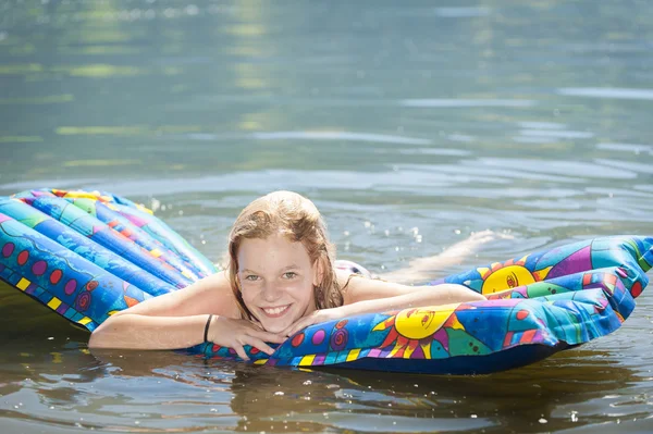 Female teenager swims in water on inflatable mattress — Stock Photo, Image