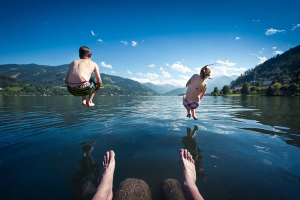 Barnen hoppa i blå sjön på sommardag — Stockfoto