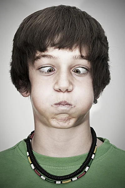 Portrait of cross-eyed young teenager boy with necklace and green pullover — Stock Photo, Image