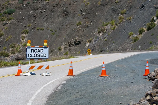 Cartello stradale chiuso su strada con coni stradali arancioni e lampeggianti — Foto Stock