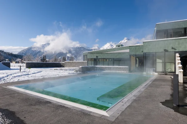 Outdoor pool which is steaming at a cold and clear winter day and mountains in the background — Stock Photo, Image