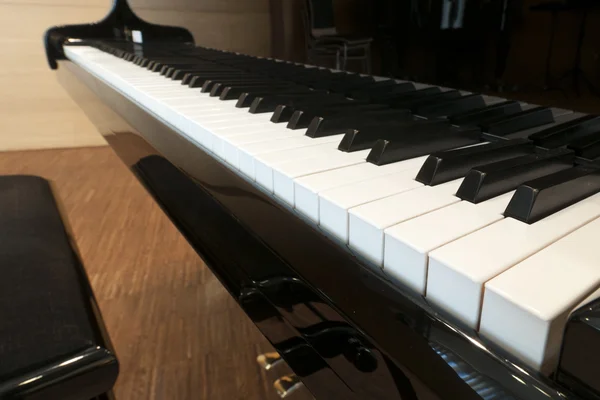 Tasti bianchi della tastiera di un pianoforte a coda concerto nero con sgabello e pedali — Foto Stock