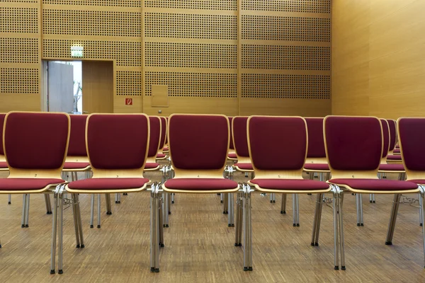 Cadeiras acolchoadas vermelhas prontas para assentos em uma sala de concertos — Fotografia de Stock