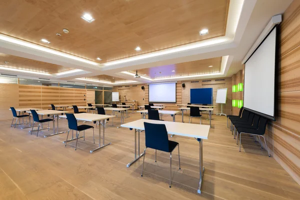 Salle de conférence moderne en bois avec tables et chaises et écran de projecteur — Photo