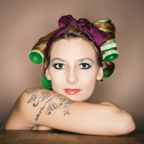 Fiatal lány tetoválás a karját, és a haj roller — Stock Fotó