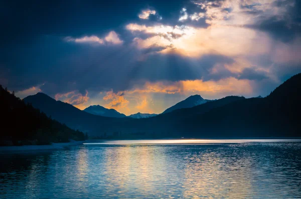 Mystic mood at austrian lake with clouds where sunbeams shine through — Stock Photo, Image