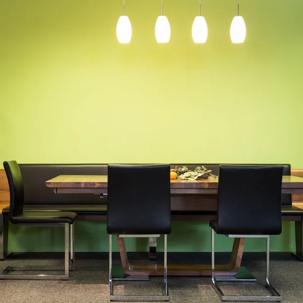 Cantilever chairs at timber table with lamps and green wall — Stock Photo, Image