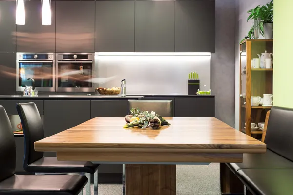 Mesa de comedor con sillas de cuero y cocina moderna gris oscuro — Foto de Stock