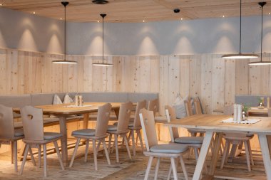 Hafif ahşap mobilyaları, yumuşak ışıklandırması ve gri kumaş panelleri olan güzel bir yemek salonu.