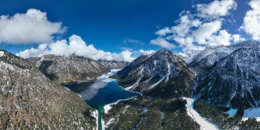 dark blue icy water and snowy alps mountains of tyrol's natural jewel lake plansee