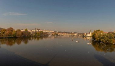 Güneşli bir günde, Prag şehrinde Charles Köprüsü ve Vltava Nehri 'nin yüzeyinde bir tekneyle manzarası.
