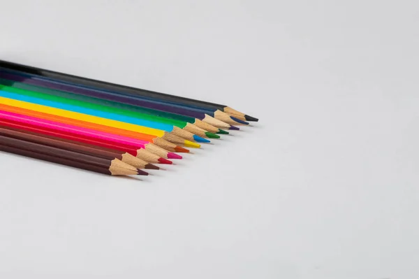 Colored crayons on a white background. The crayons are brown, black, yellow, orange, blue, purple.