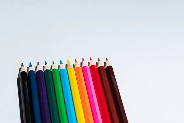 Colored crayons on a white background. The crayons are brown, black, yellow, orange, blue, purple.