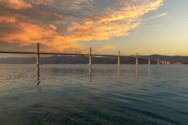 Hırvatistan 'ın Peljesac adasıyla Avrupa arasında güzel, modern bir köprü. Arkaplanda dağ sıraları ve bulutlu güzel bir gökyüzü.