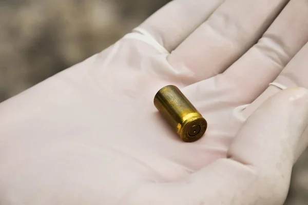 Pistol\'s bullet shells in palm of investigator or police officer, concept for keeping physical evidences from pistols, guns and bullet shells at the point of the murder, soft and selective focus.