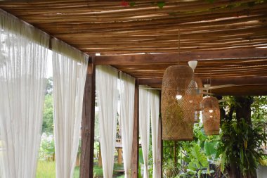 Bamboo lantern which has bulb inside and hanging on the ceiling of relaxing area, soft and selective focus.