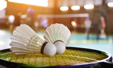 White cream shuttlecocks on rackets beside the badminton court, concept for badminton lovers around the world. Selective focus on right shuttlecock.