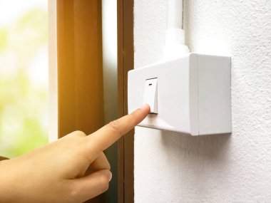 Kadın ev sahibi tuvaletin önündeki ışık düğmesi panelini kapatmak için elini kullanıyor. Tuvaleti kullandıktan sonra, yumuşak ve seçici odak noktası, küresel ısınma kavramı..