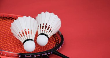 Beyaz badminton topu ve raket kırmızı zeminde, badminton kortunda, kopyalama alanı, mekik horozlarına yumuşak ve seçici odaklanma.