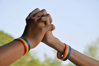 Bulanık geçmişi olan Asyalı erkek çiftlerin bilekliklerinde gökkuşağı lastiği bileklikler. Gururlu bir ayda veya Haziran 'da tüm dünyada Lgbtq + topluluğunu kutlamak için konsept..