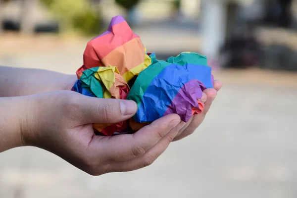 虹色の紙で作られた紙のボールはLgbtの人の手に持っています 世界中の誇りの月にLgbtq コミュニティのお祝いのための概念 — ストック写真