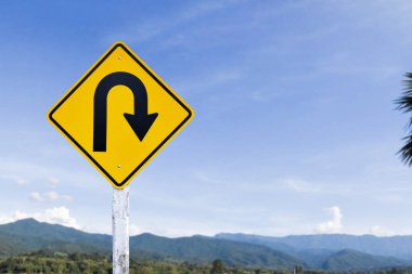 Trafik işareti: Kırsal yolun yanındaki çimento direğinde sağa U dönüşü işareti, beyaz bulutlu mavi arka plan, boşluğu kopyala.